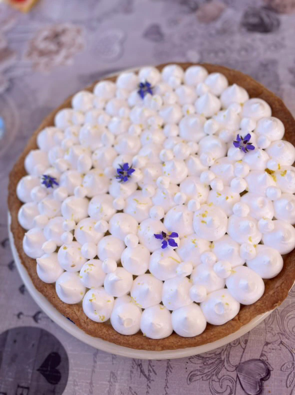 Tarte décorée de crème et de petites fleurs violettes