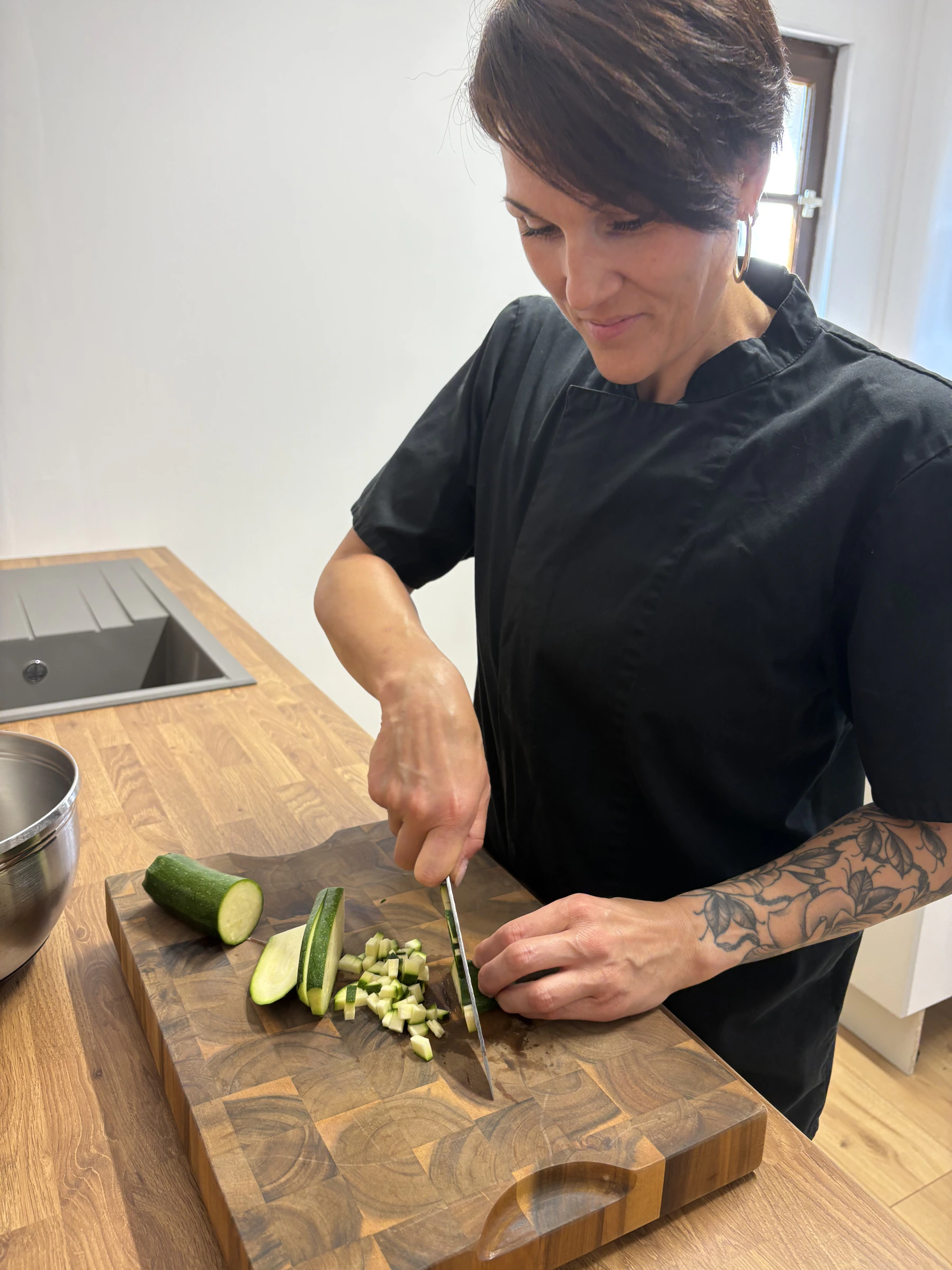 Émilie découpant des courgettes sur une planche en bois
